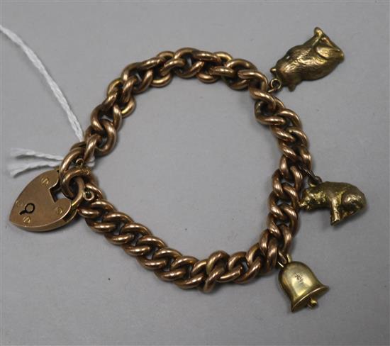 A yellow metal curb-link bracelet with padlock clasp, hung with three charms (all tests as 9ct).